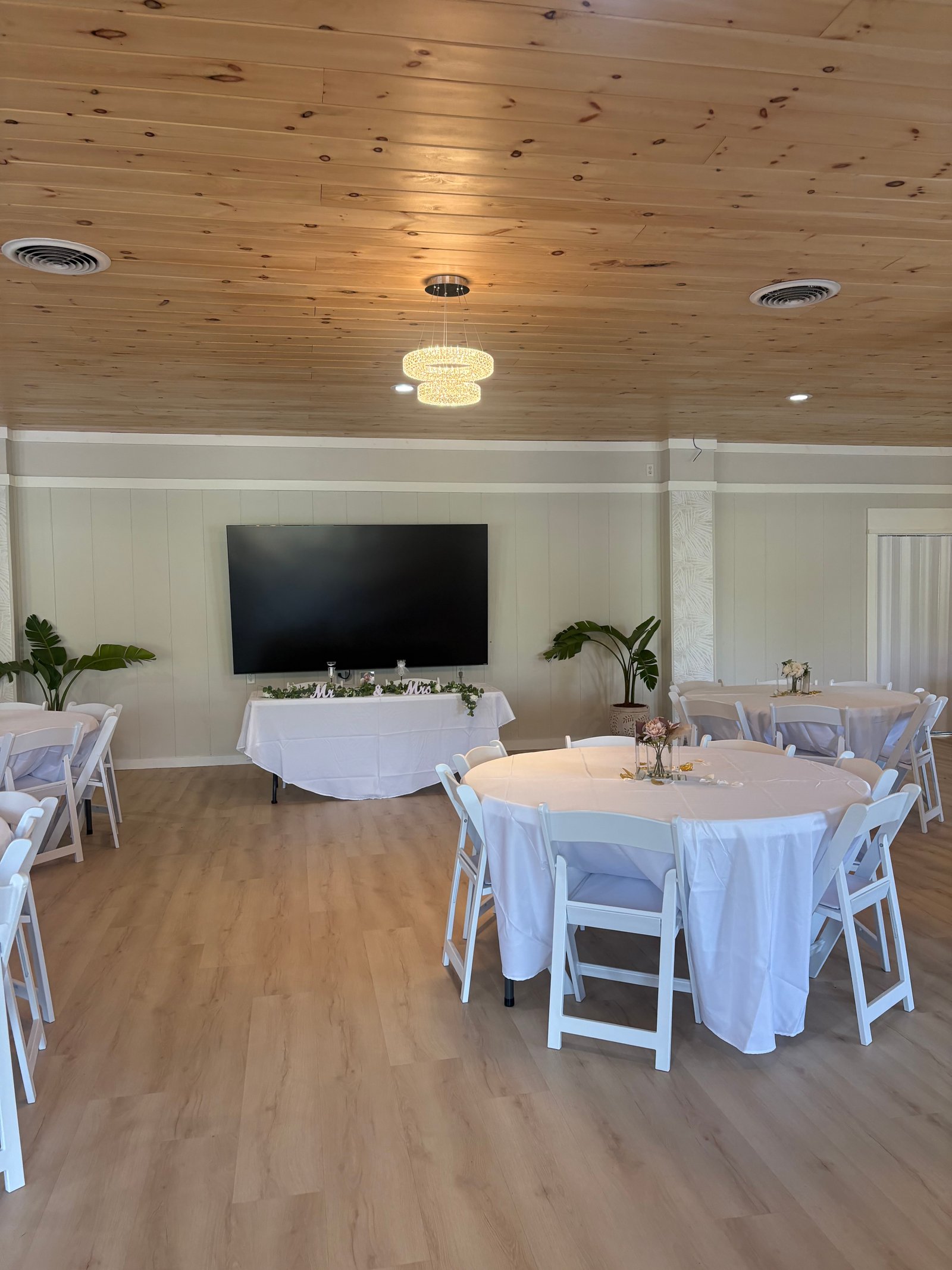 Interior setup at MeetUps Event Center with a large wall-mounted screen and round table seating for meetings, seminars, and business events